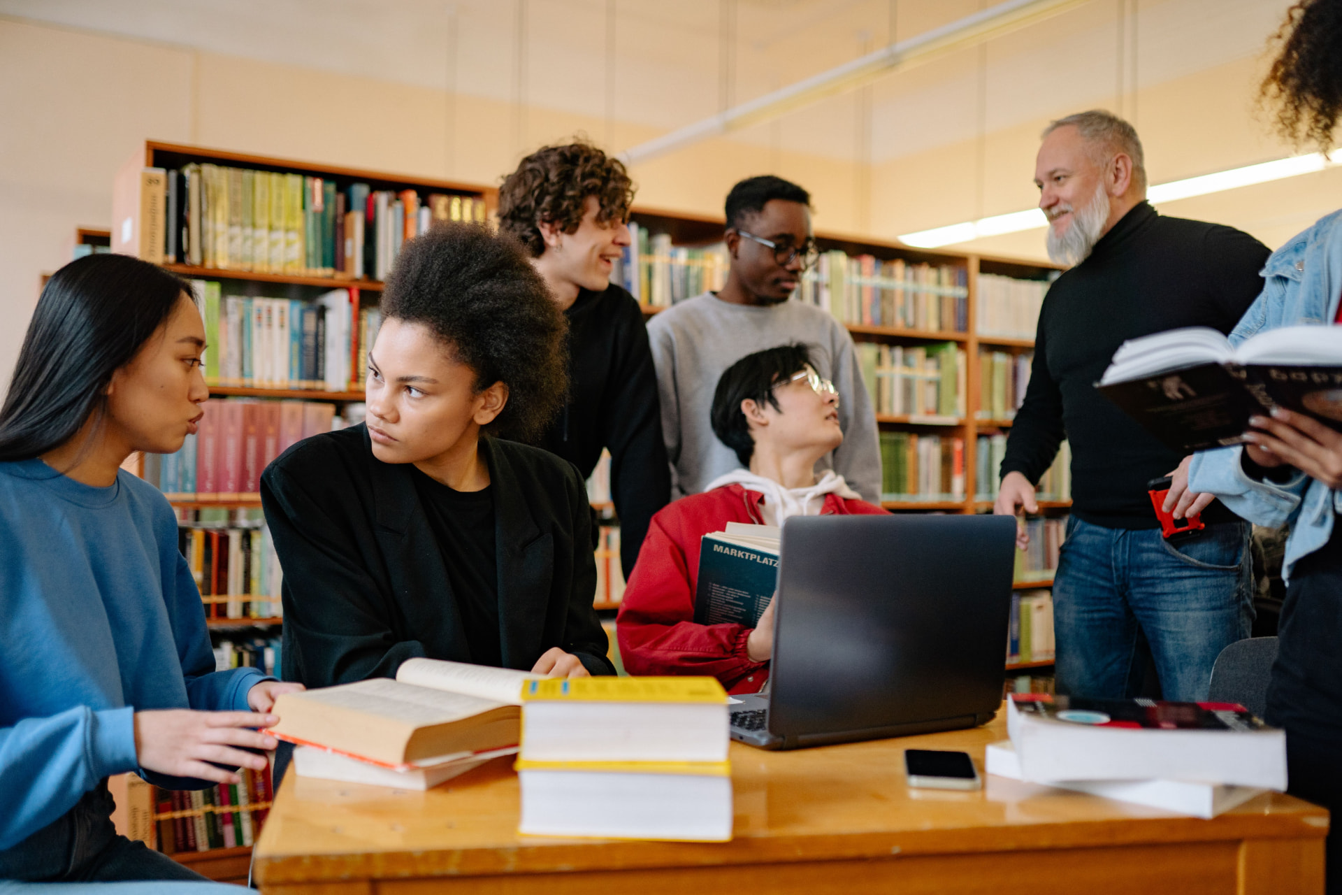 A research group working through a paper together around a table of books and a laptop