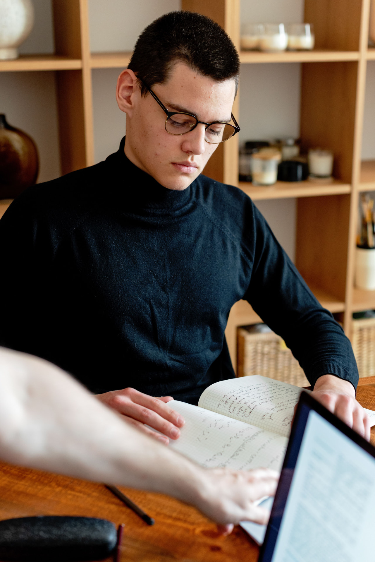 A researcher working through handwritten notes beside a tablet